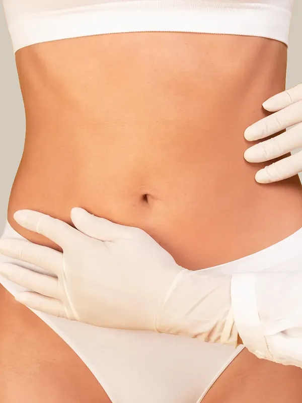 Girl in bikini with doctor's hands on abdomen.